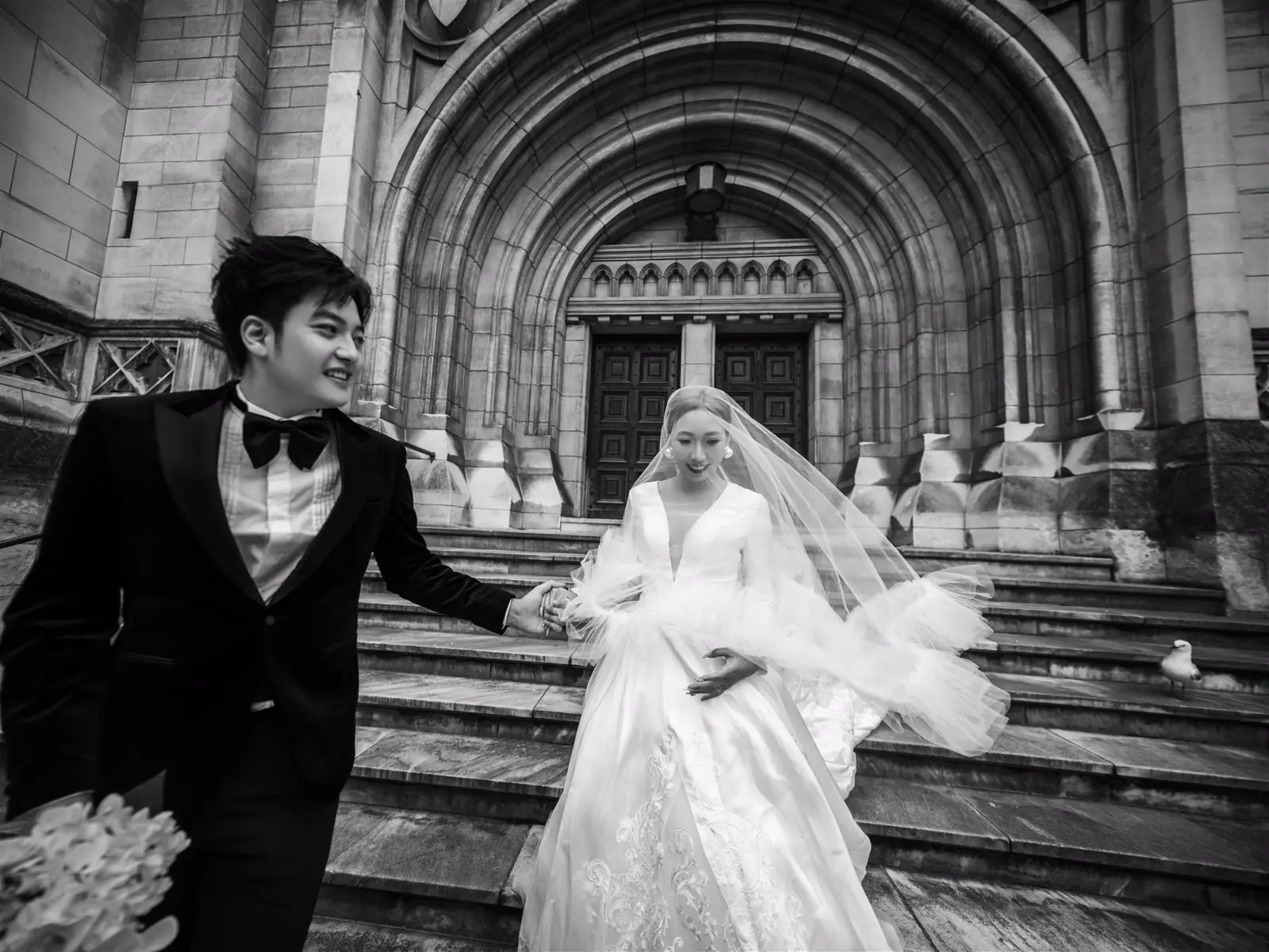 Black-and-white wedding portrait with a dark suit and bow tie